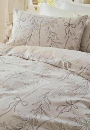 Beiges Bettwäsche-Set mit botanischen Linienzeichnungen von Blättern, Beeren und Schleifen auf dem Bettbezug und passenden Kissen.