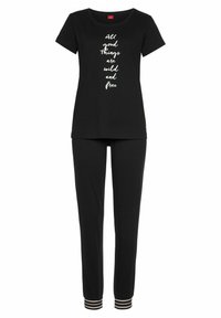 Schwarzes Pyjama-Set mit einem T-Shirt, auf dem in weißer Schrift "Alle guten Dinge sind wild und frei" steht, und einer Hose mit gestreiften Bündchen.