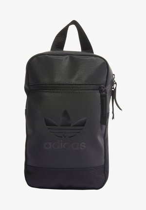 Sac à dos Adidas noir en matière lisse, compartiment zippé et logo embossé. Design compact avec une poignée supérieure et une base texturée.
