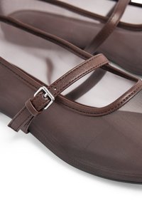 Brązowe baletki z siateczkową górą, z skórzaną klamrą i srebrnym zapięciem. Okrągły czubek i gładka faktura. Subtelne detale w postaci szwów.
