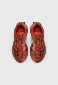 Ténis de atletismo vermelhos e laranja, com material em malha e sintético, sola texturizada e um design com atacadores e alças.