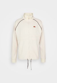 Veste écrue zippée avec col montant, passepoil noir sur les manches, petit logo rouge et orange sur la poitrine, et cordons au bas.