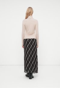Svetlo bež turtleneck v kombinaciji z dolgo črno krilo, ki ima diagonalne bele in sivo stripe. Obleka dopolnjujejo masivni črni škornji.