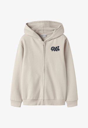 Felpa con zip color beige chiaro, con grande cappuccio e cerniera frontale, con stampa grafica "COOL" in blu scuro sul petto. Tessuto dalla texture morbida.