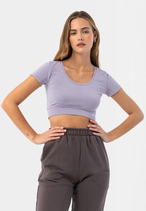 Světle fialový crop top s kulatým výstřihem a krátkými rukávy, v kombinaci s tmavě šedými vysokými kalhotami. Měkký materiál s těsným střihem.