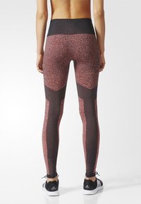 Leggings de cintura alta en un patrón jaspeado de rosa y negro, con una cinturilla texturizada y detalles en malla negra a lo largo de los lados.