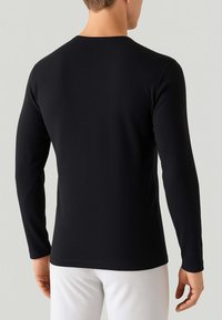 Maglietta nera a maniche lunghe realizzata in tessuto elasticizzato. Presenta un collo a giro e una forma aderente, con una texture liscia e cuciture minime sul retro.