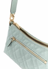 Sac bandoulière en cuir bleu clair matelassé avec deux fermetures éclair dorées, une bandoulière amovible et une texture lisse. Comprend une petite étiquette près de la fermeture éclair.