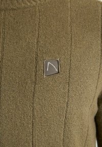 Pulover tricotat de culoare verde măsliniu, cu un model vertical în dungi și o mică etichetă pătrată cu un design simplu dintr-o linie albă pe piept.