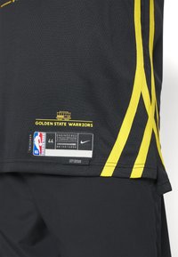 Jersey de baloncesto de malla negra con acentos y rayas amarillas. Incluye logo, etiqueta de tamaño y etiqueta "City Edition" en la parte inferior.