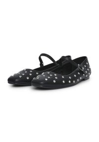 Schwarze flache Schuhe mit spitzen Zehen, verziert mit silbernen Nieten, mit dünnen Knöchelriemen und Schnallenverschluss.