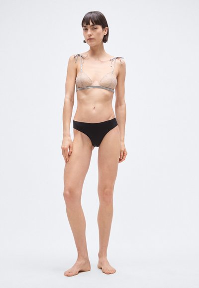 Kolmnurkne rinnahoidja läbipaistvast geomeetrilisest võrgust hallide detailide ja reguleeritavate nöörrihmadega, millele on lisatud mustad kõrge vöökohaga bikiinipüksid.