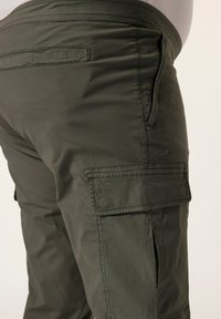 Oliivinvihreät cargo-housut, joissa on sileä pinta, sivutasku ja takatasku, joustava vyötärö ja ommellut saumat.