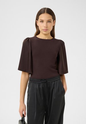 Ruskea istuva toppi, jossa on sifonkiset puffihihat, pyöreä pääntie ja sileä pinta. Yhdistetty mustiin, rennosti istuviin, naruhaarukkapö trousers.
