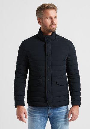 Marineblauer, gesteppten Jacke mit hohem Kragen, Frontknöpfen und zwei seitlichen Aufsatztaschen. Hergestellt aus einem glatten, leichten Material.