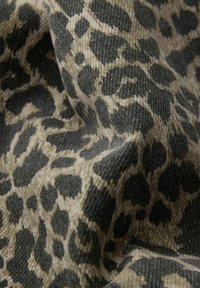 Tkanina s leopardím vzorom s textúrovaným povrchom v odtieňoch béžovej a tmavošedej, ktorá zobrazuje rôzne veľkosti a vzory škvŕn.