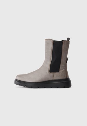 Grå suede ankelstøvel med svart elastisk sidepanel og tykk svart såle, vist fra venstre side.