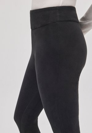 Leggings negros acanalados con una cinturilla ancha, diseño ajustado y textura suave, que resaltan una silueta elegante.