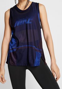 Canotta a rete blu con grande logo "NIKE", orlo curvo e fessure laterali per la ventilazione. Tessuto liscio con accenti a motivo geometrico.