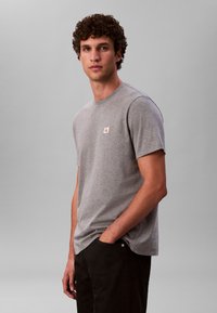 Siva kratka majica s kratkim rukavima od pamučne mješavine s okruglim izrezom, s malim logotipom na prsima i opuštenim krojem.