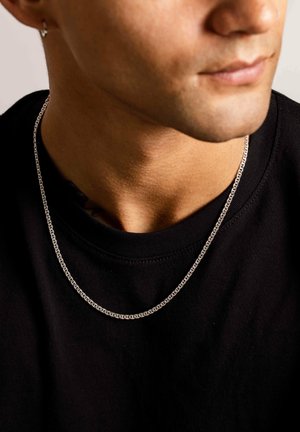 Sølvkæde på en sort t-shirt; har et fladt, rektangulært led-design med en poleret overflade og subtil tekstur.