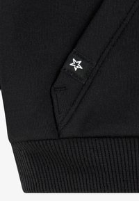 Black sweatshirt featuring ribbed cuffs and hem, smooth knit texture, and a small label with a white star logo on the sleeve.