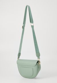 Borsa a spalla in ecopelle verde con forma curva, chiusura a patta, tasca frontale e tracolla regolabile con logo. Accenti in metallo dorato.
