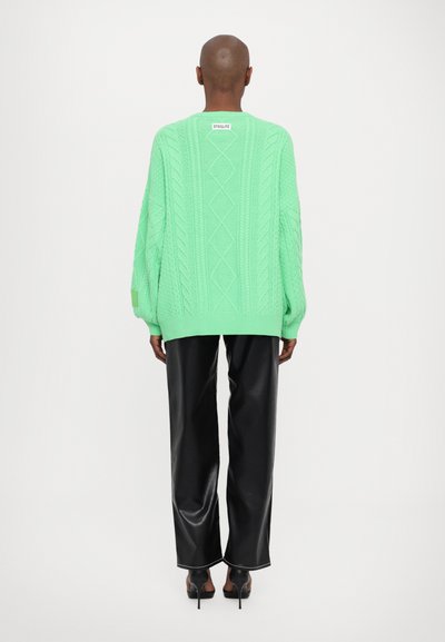 Maglione verde a maglia grossa con vestibilità oversize, dotato di una schiena quadrata, motivi testurizzati e dettagli con etichetta. Abbinato a pantaloni in pelle nera.