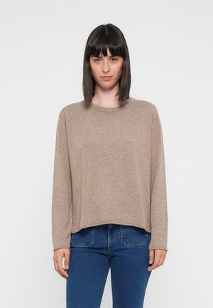 Beżowy sweter z długim rękawem, okrągłym dekoltem, teksturowanym materiałem i luźnym krojem, w zestawieniu z niebieskimi dżinsami. Prosty i casualowy design.