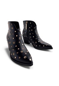 Bottes noires en cuir à la cheville avec des accents dorés ronds, un bout pointu et une fermeture éclair sur le côté. Talon épais pour plus de stabilité et de confort.