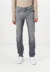 Gray denim jeans with a slim fit, five-pocket design, and subtle fading. Finished with a classic button and zipper closure.