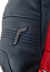 Läderhandske med marinblå och röda färger, strukturerad yta, synliga sömmar och en svart logotyp som accent.