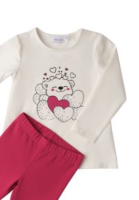 Cremfarbendes Langarmshirt mit einem lächelnden Bären, umgeben von Herzen, kombiniert mit knallpinken elastischen Hosen.
