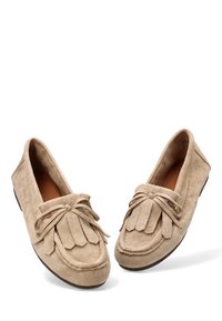 Zapatos de ante beige estilo mocasín con punta redonda, detalle de flecos en el frente y suela plana de goma. Cordones atados en la parte delantera.