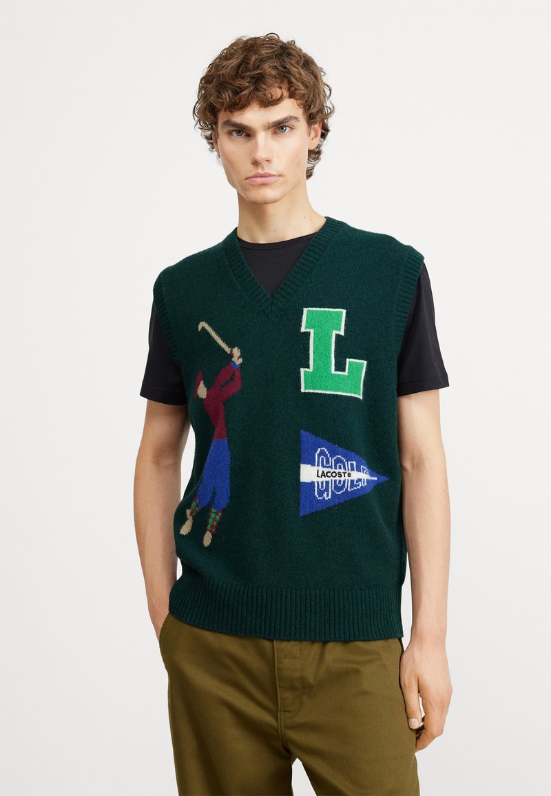 Maglione estivo senza maniche di colore verde con una grafica di un golfista, una grande lettera "L" e il logo Lacoste su un accento triangolare blu.