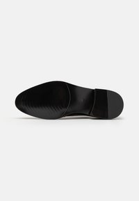 Suela de zapato de piel negra con un acabado liso, puntera redondeada y una sutil textura acanalada para un mejor agarre. Incluye un tacón bajo y cuadrado.