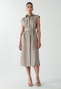 Taupe Hemdkleid mit vertikalen Streifen, kurzen Ärmeln, Taillengürtel und zwei vorderen Taschen. Glattes Material mit lockerer Passform, knielang.