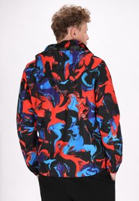 Kleurvolle geprinte jas met een zwarte basis en abstracte rode, blauwe en paarse swirls. Inclusief een capuchon en elastische cuffs.