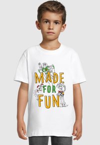 Hvid bomulds T-shirt med farverig grafisk tekst "MADE FOR FUN" og tegneseriefigurer, herunder Buzz Lightyear og Woody, i omridsdesign.
