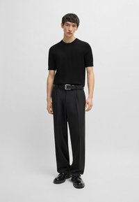 Black short-sleeve knit shirt and loose-fitting black trousers, paired with a black belt featuring a silver buckle, and black shoes.