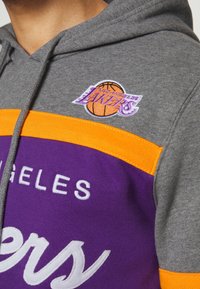 Felpa con cappuccio grigia con un motivo viola e arancione. Include il logo ricamato "Los Angeles Lakers" e il testo in bianco. Realizzata in tessuto morbido.