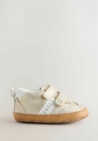 Baskets en similicuir doré clair avec deux bandes Velcro réglables, accents blancs, panneaux latéraux texturés et semelle en caoutchouc.