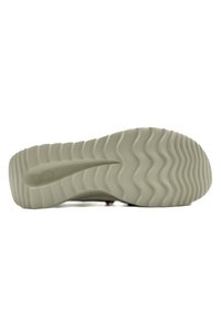Shoe sole featuring a thick, textured rubber material in a light beige color with a wavy tread pattern for grip and traction.