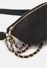 Bolso de cuero negro acolchado con cremallera dorada y strap de cadena entrelazada en cuero negro y dorado sobre un fondo blanco.