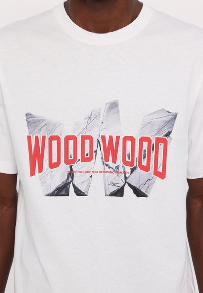 Balta medvilninė marškinėliai su grafiniu dizainu, kurioje yra tekstas "WOOD WOOD" ryškiai raudona spalva su sutrūkinėjusio akmens efektu. Trumpomis rankovėmis.