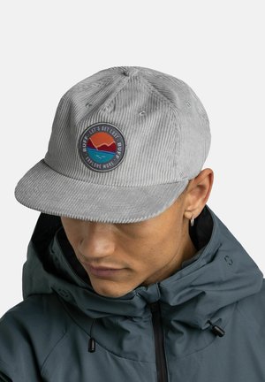 Grau Cordhutrapp mit flachem Schirm und einem runden Patch mit Landschaftsdesign. Getragen mit einer dunklen, mit Reißverschluss versehenen Jacke.