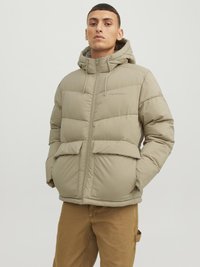 Beige pufferjakke med hætte, frontlynlås, to store frontlommer og justerbare snore, designet med en quiltet tekstur.