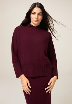 Vinrød strikket sweater med hætte, ribbet kant og vide ærmer, kombineret med et matchende nederdel. Glat tekstur og afslappet pasform.