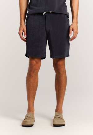 Marineblauwe, knielange shorts van zachte stof met een elastische tailleband en trekkoord. Heeft zijzakken en een eenvoudige zoom.