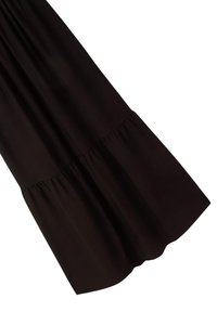 Abito nero con un design fluttuante e a strati. Il tessuto ha una consistenza liscia. L'orlo è arrotondato sul fondo con arricciature alla cucitura della vita.